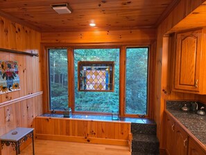 L’intérieur de la cabane est doté de murs en bois, d’un banc, d’une fenêtre ornée de vitraux et d’un coin cuisine avec des plans de travail en granit.