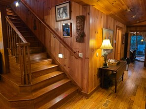 A wooden staircase leading to a second floor, a wall-mounted lamp, and a framed picture on the wall.