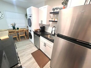 A modern kitchen with stainless steel appliances, white cabinetry, and a black countertop. - Peaceful Longwood Home - Minutes to Attractions (Longwood)