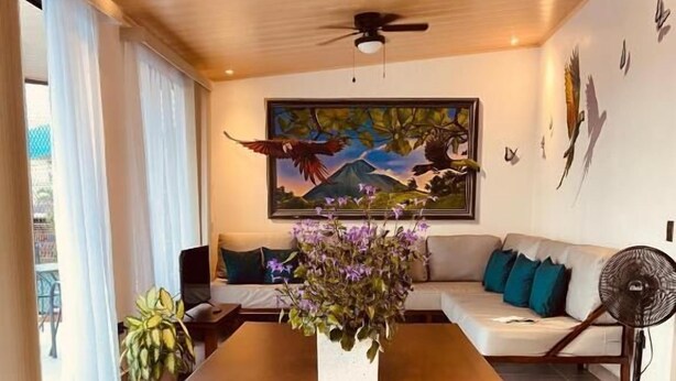 A spacious room with a long wooden table, a sofa, and a painting on the wall.