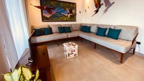 A living room with a sectional sofa, a painting of a bird, and a ceiling fan.