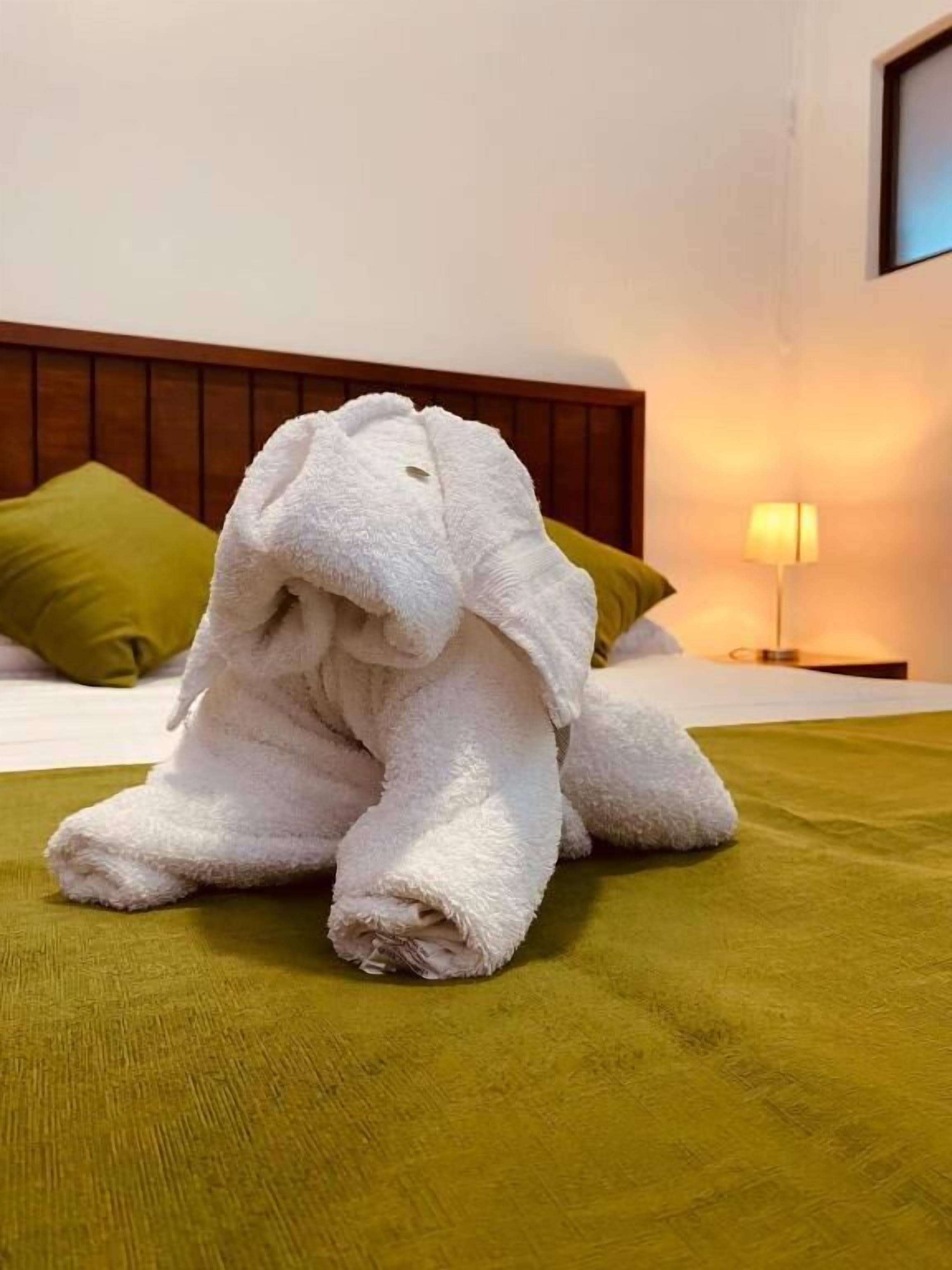 Een bed met een groene dekbedovertrek, een witte handdoek en een groen kussen.