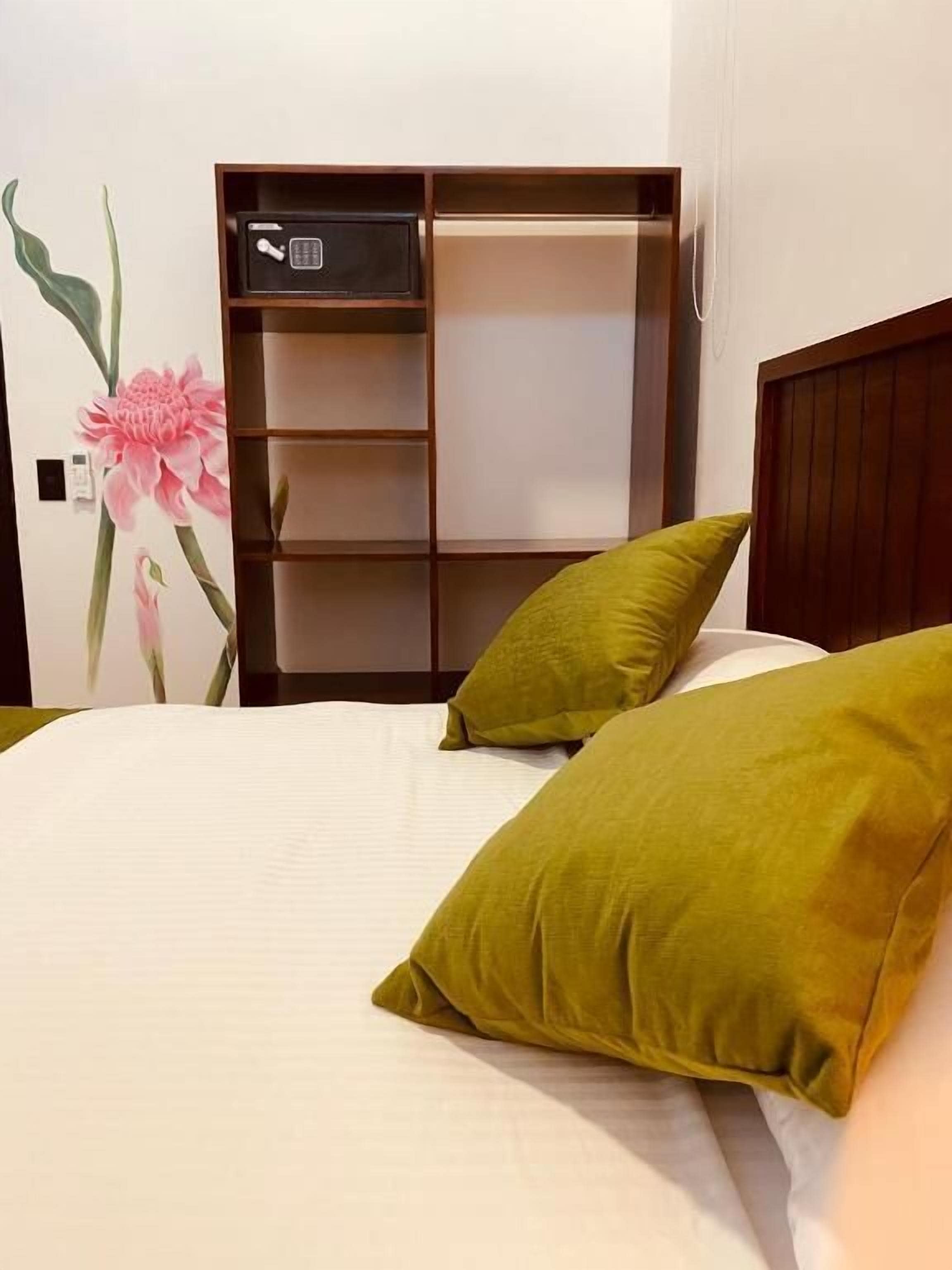 Een bed met twee kussens, een houten hoofdbord en een ingebouwde plank met een klein elektronisch apparaat.