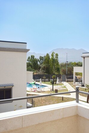 A residential area with a swimming pool, lounge chairs, and a view of distant mountains. - Appartamento "Isola di Maraone" (Carini)