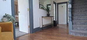 A hallway with a wooden floor, a radiator, a potted plant, a bench, and a staircase. - Contractors paradise in Peterborough -sleeps 14 (Peterborough)