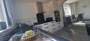 A modern kitchen with a built-in microwave, a kettle, and a coffee maker. There is a sink with a dish rack and a window providing natural light. - Contractors paradise in Peterborough -sleeps 14 (Peterborough)