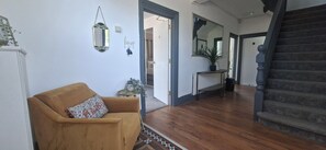 A living room with a sofa, a small table with a plant, and a staircase.
