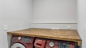 A laundry room with two front-loading washing machines and a wooden countertop.