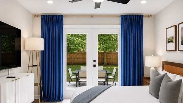 A bedroom with a bed, a TV, a lamp, and a view of a backyard with a table and chairs. - Blue Raider Bungalow | 3 Min to MTSU | 35 min to Nashville (Murfreesboro)