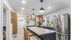 A modern kitchen with a central island, stainless steel appliances, and pendant lighting. - Blue Raider Bungalow | 3 Min to MTSU | 35 min to Nashville (Murfreesboro)