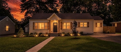 A two-story house with a front porch, a driveway, and a well-maintained lawn.