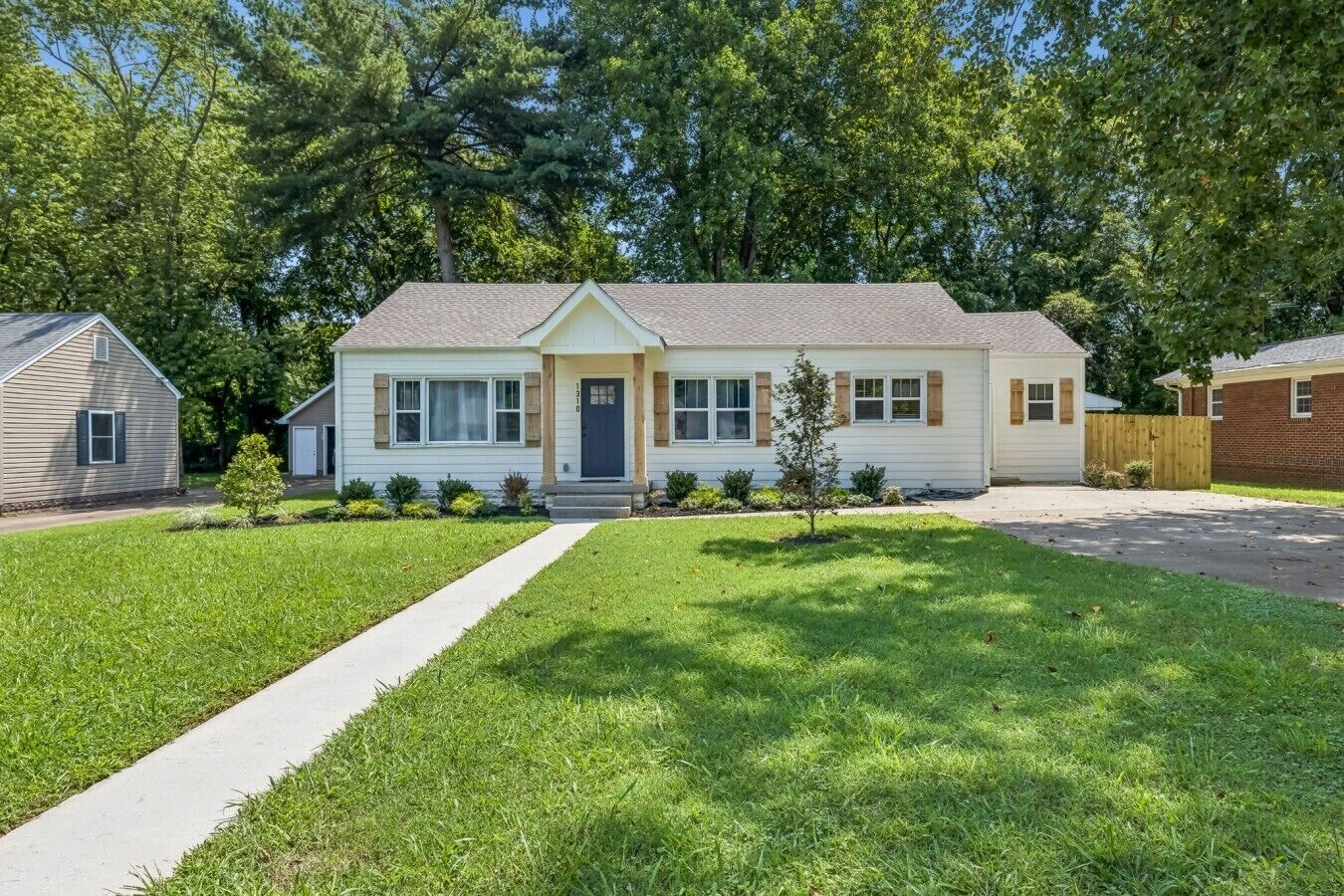 A two-story house with a front porch, a driveway, and a well-maintained lawn.
