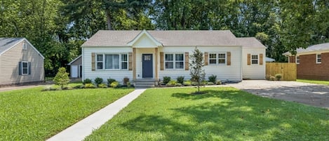 A two-story house with a front porch, a driveway, and a well-maintained lawn.