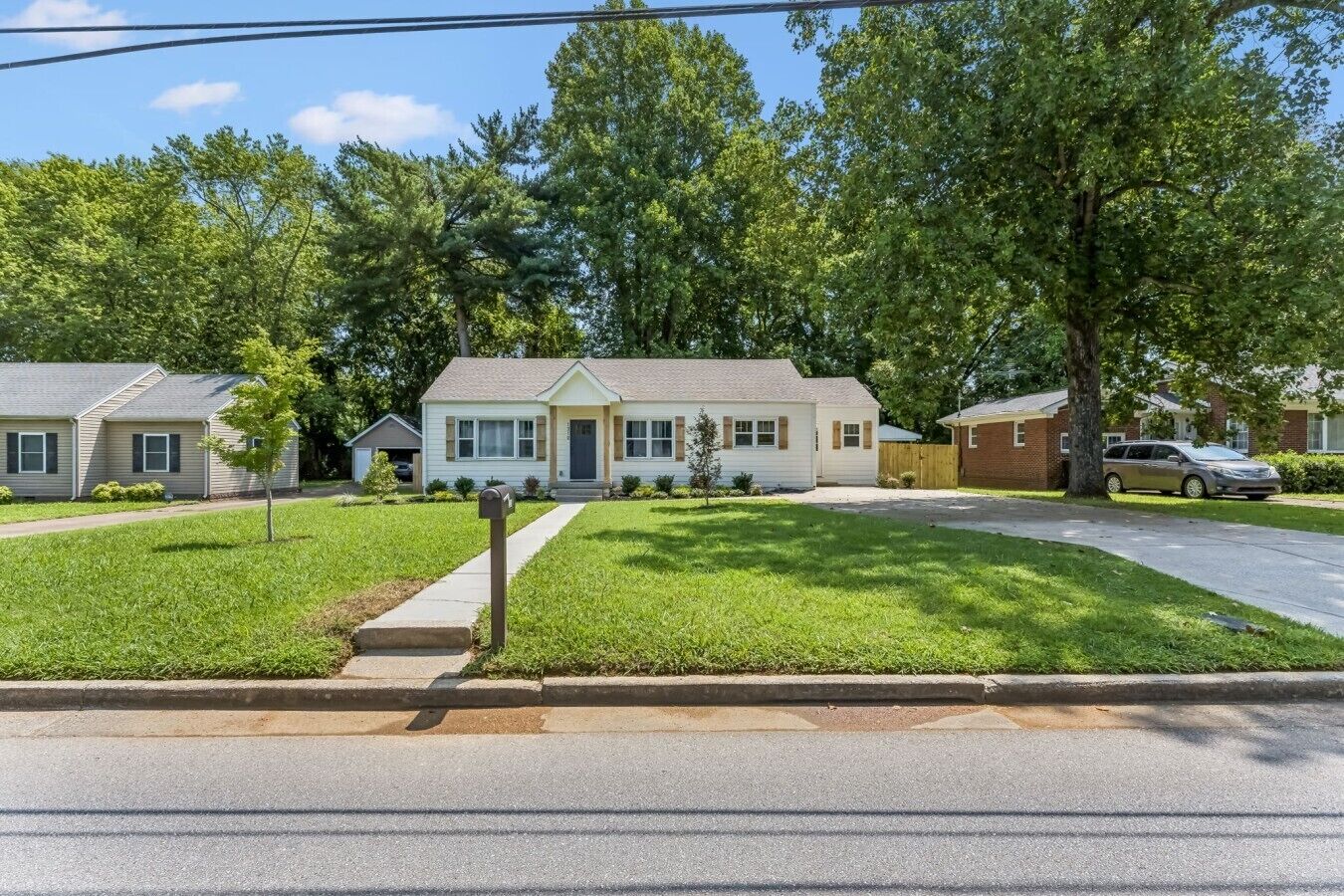 A residential area with single-family homes, a driveway, and a sidewalk.