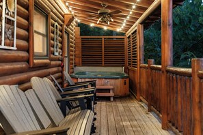 A wooden cabin with a hot tub, wooden benches, and a ceiling fan. - Orso’s Den, Mountain Views, Theater, Arcade, Hot Tub & Free L2 EV Charging! (Pigeon Forge)