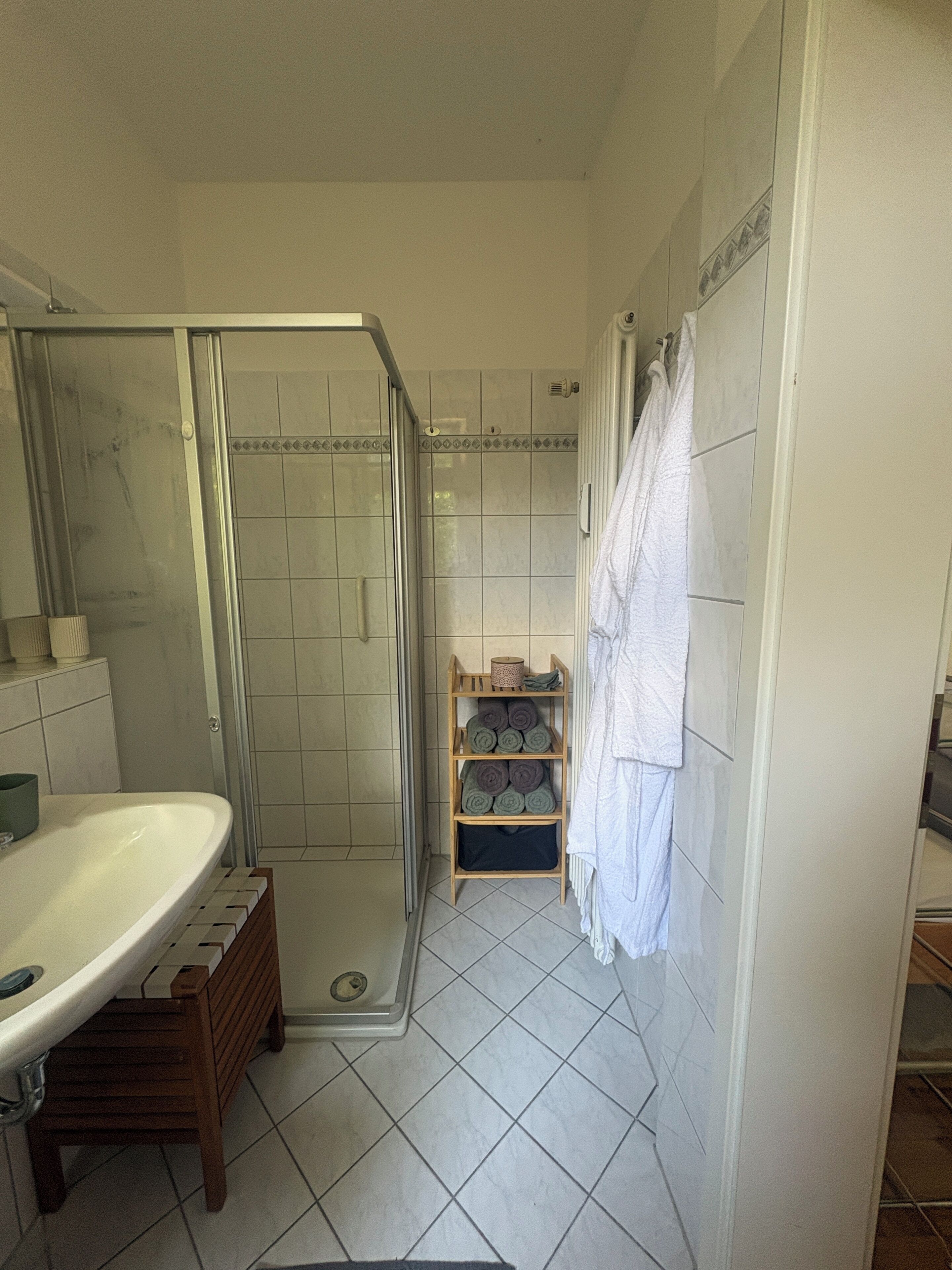 Un baño con ducha, lavamanos y toallero.
