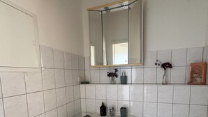 Ett badrum med ett vitt handfat, en spegel och kaklade väggar.
