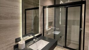 A modern bathroom with a glass-enclosed shower, a dark countertop sink, and a large mirror. - Casa Valentina (Aguascalientes)