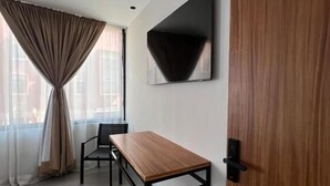 A modern room with a wooden table, a chair, a TV mounted on the wall, and a door. - Casa Valentina (Aguascalientes)