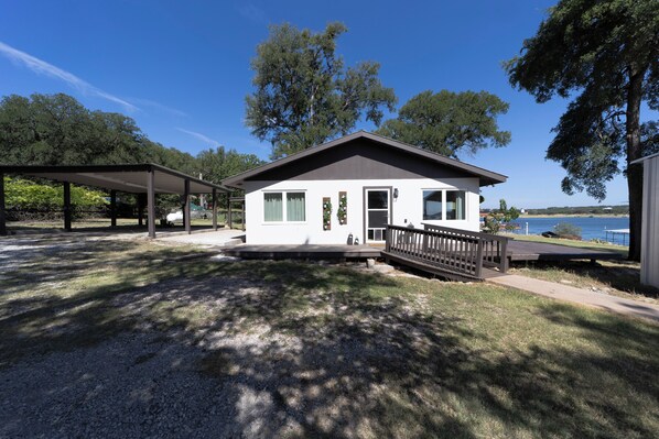 A two-story cabin with a covered patio and a deck overlooking a body of water.