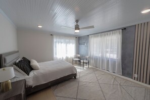 A bedroom with a bed, a desk, a chair, and a ceiling fan.