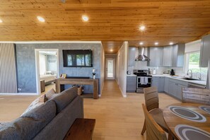 A modern kitchen with wooden cabinets, a built-in oven, and a dining area with a wooden table and chairs.