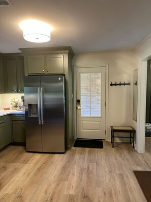 A kitchen with a stainless steel refrigerator, light green cabinets, a white door with a window, and a small wooden bench. - NEW!!!  Freshly renovated 3-bed/2-bath cottage close to Sardis Lake and Ole Miss (Sardis)