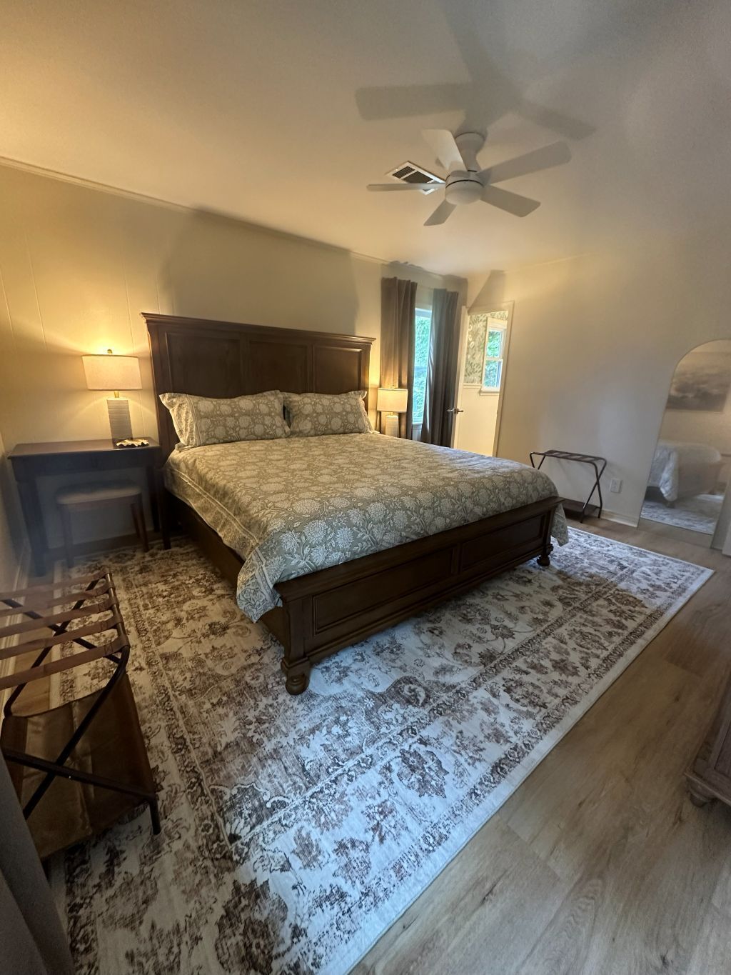 Un dormitorio con una cama, mesitas de noche, ventilador de techo, alfombra y una silla.