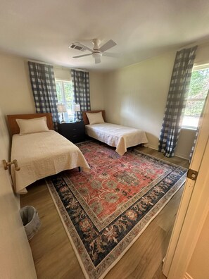 A room with two beds, a ceiling fan, a patterned rug, and checkered curtains. - NEW!!!  Freshly renovated 3-bed/2-bath cottage close to Sardis Lake and Ole Miss (Sardis)