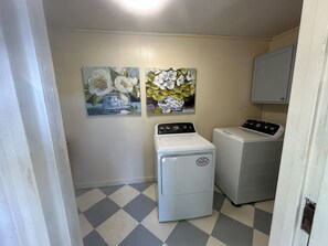 Ein Waschraum mit zwei Waschmaschinen, Fliesenboden und zwei floralen Bildern an der Wand.