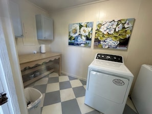 A laundry room with a washing machine, a drying machine, a sink, and a trash bin. There are two paintings on the wall. - NEW!!!  Freshly renovated 3-bed/2-bath cottage close to Sardis Lake and Ole Miss (Sardis)