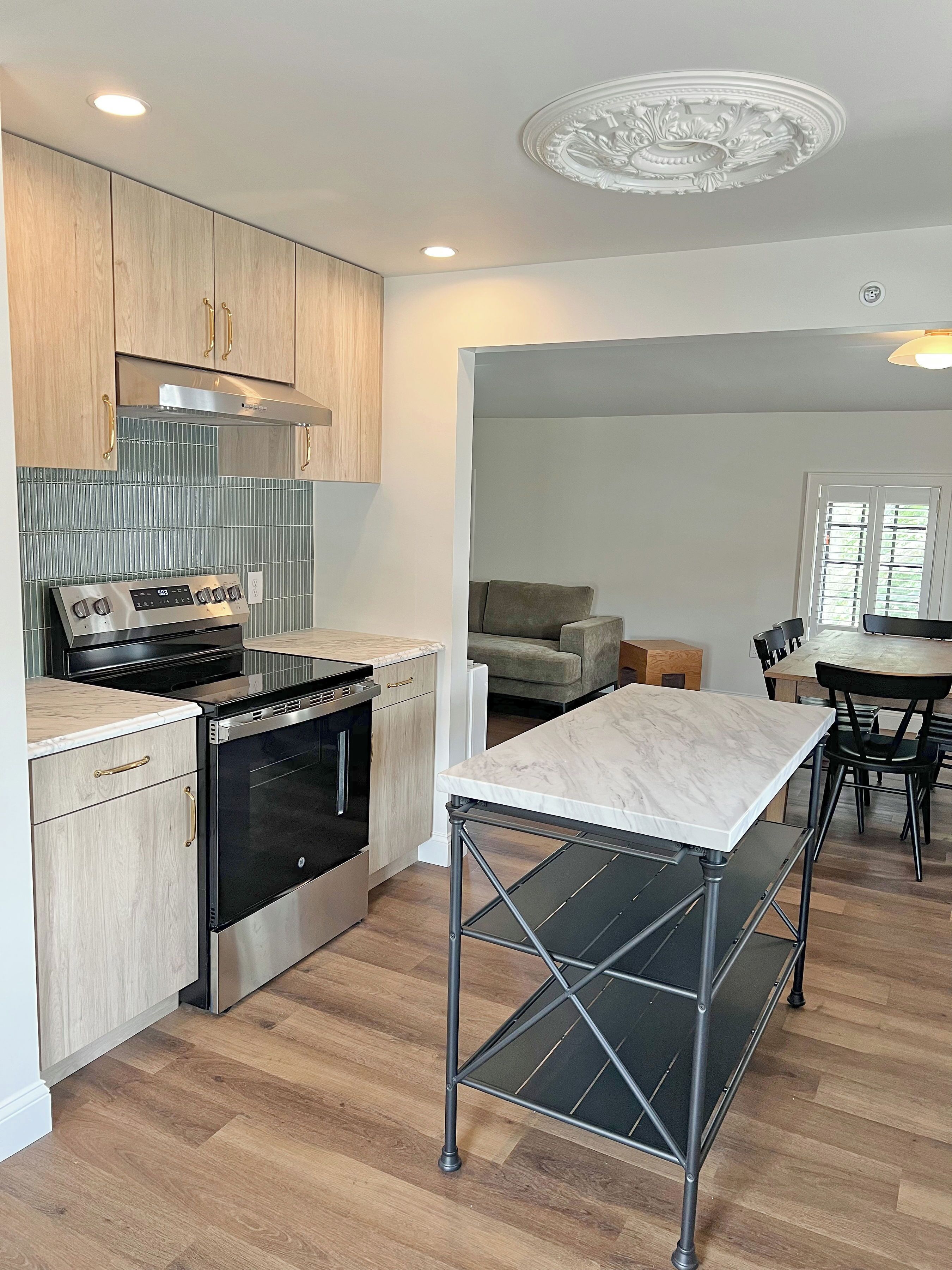 A modern kitchen with stainless steel appliances, wooden cabinets, and a marble countertop.