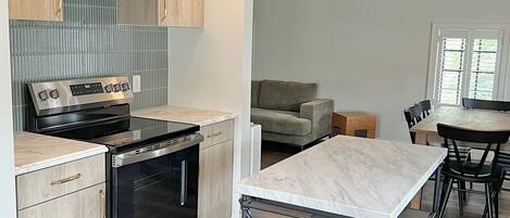 A modern kitchen with stainless steel appliances, wooden cabinets, and a marble countertop.