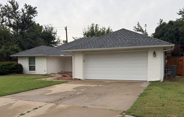 A residential house with a garage, a driveway, and a lawn.
