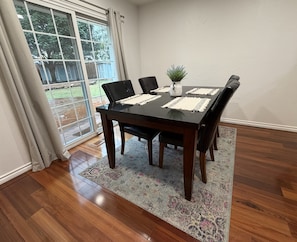 Un comedor con una mesa de madera oscura, sillas negras y un tapete estampado.