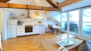 A modern kitchen with white appliances, wooden beams, and a dining area with a glass table.