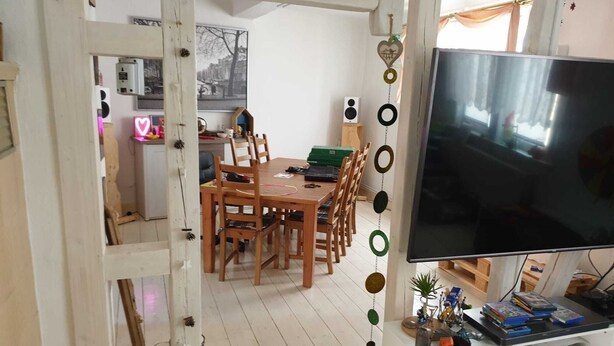 A room with a dining area, a TV, and a white cabinet with various items.