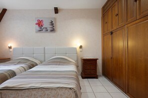 A bedroom with a bed, bedside tables, a nightstand, a wooden wardrobe, and a wall-mounted artwork.