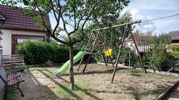A residential area with a swing set, a slide, and a bench.
