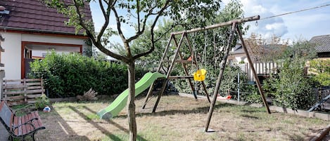 A residential area with a swing set, a slide, and a bench.