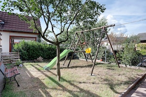 A residential area with a swing set, a slide, and a bench.