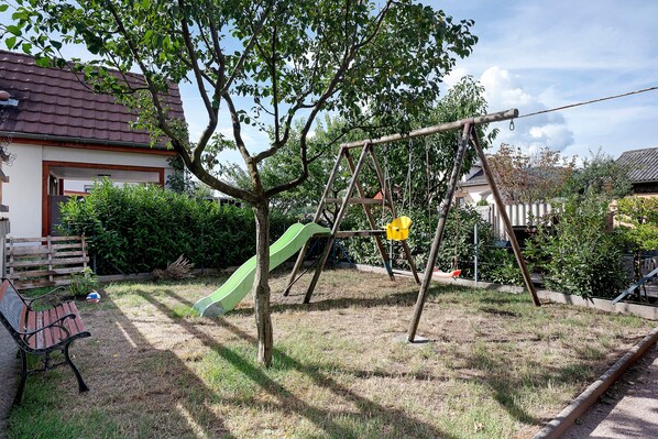 A residential area with a swing set, a slide, and a bench.