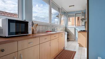 A modern kitchen with wooden cabinets, a microwave, and a view of the outside through large windows.