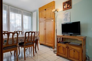 Un comedor con una mesa y sillas, un armario de madera, un televisor sobre un mueble bajo y un mapa colgado en la pared.
