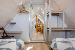 A bedroom with two beds, a wooden chair, and a mirror.