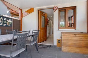 A dining area with a table and chairs, a wooden cabinet, and a door leading to a hallway.