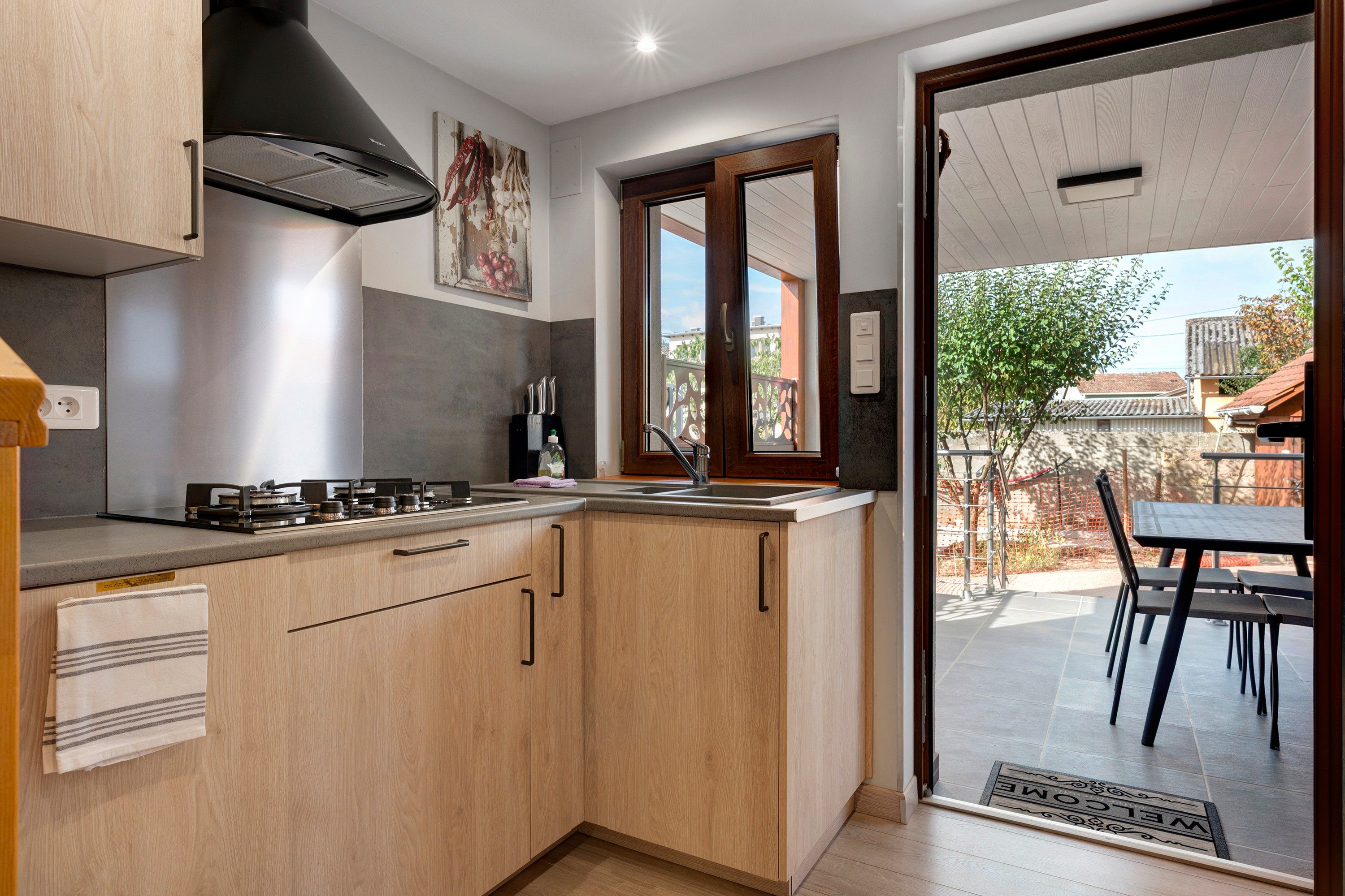 A modern kitchen with a gas stove, wooden cabinets, and a view to an outdoor patio.