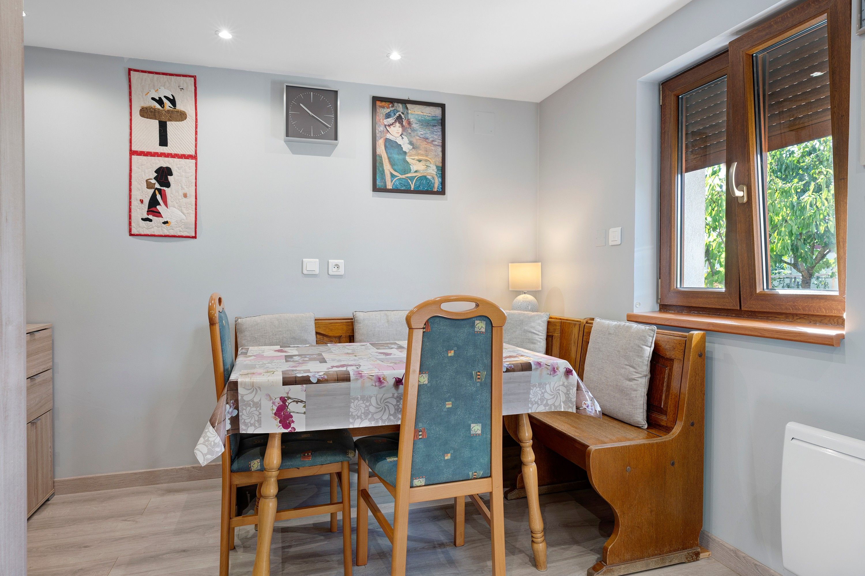 Een eetgedeelte met een tafel, stoelen, een bank en kunstwerken aan de muren.