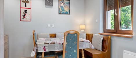 A dining area with a table and chairs, a bench, and artwork on the walls.