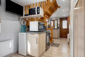 A compact kitchen with a microwave, a small refrigerator, and a sink.